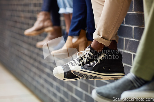 Image of Brick wall, student sneakers and friends outdoor on university campus together with feet. Relax, urban youth and foot at college with people legs ready for education, study and shoes while sitting