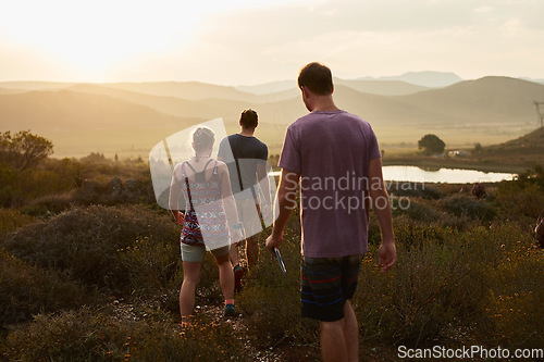 Image of Friends hiking, walking in countryside at sunset with fitness and bonding in nature with travel and freedom. Exercise, adventure with men and woman walk through meadow or field with back view