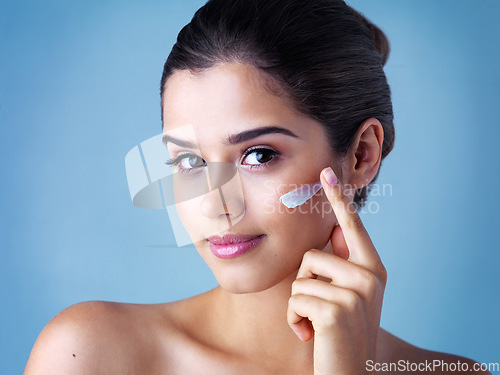 Image of Skincare, portrait of woman with face cream and in blue background. Beauty, cosmetic treatment and happy female model pose with sunscreen for skin care or health wellness in studio backdrop.