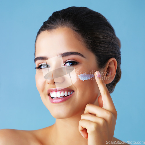 Image of Cosmetics, portrait of woman with face cream and in studio backdrop. Advertisement or marketing, beauty treatment and happy model pose for skincare protection or health wellness in blue background