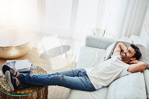 Image of Home, stretch and man on a couch, relax and freedom on a weekend break, thinking and calm in the living room. Male person, happiness and happy guy on a sofa, lounge and smile with wellness and dream