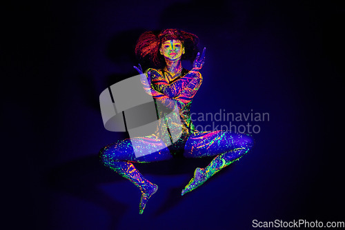 Image of Body paint, dance and portrait of a woman in neon lighting isolated on a dark background in a studio. Creative, glow and a dancing model with psychedelic art for creativity and fluorescent abstract