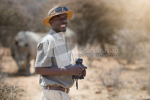 Image of Portrait, safari and wildlife with a man ranger outdoor in a game park for nature conservation. Animals, binoculars and blurred background with an african male person on patrol in the wilderness