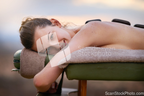 Image of Portrait, relax and massage with a woman lying in spa for wellness treatment at a luxury resort on vacation. Bed, zen or beauty and a female customer outdoor for stress relief with hot stone therapy