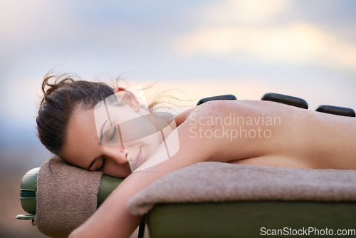 Image of Relax, massage and a woman lying in a spa for wellness treatment at a luxury resort while on vacation. Bed, zen or beauty salon and a female customer outdoor for stress relief with hot stone therapy