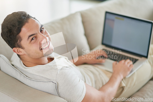 Image of Laptop, sofa and portrait of man doing remote work in his home, house or apartment with smile and relax in living room. Couch, happy and young male person or freelancer typing a project online or web