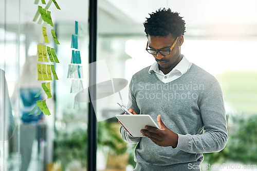 Image of Glass wall, business tablet and black man planning, research and strategy in office workplace. Technology, board and African male professional with sticky notes for online, schedule and brainstorming