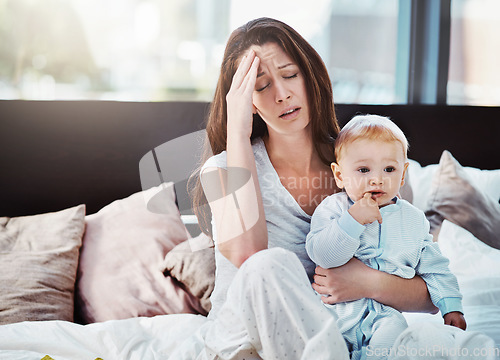 Image of Mother, baby and tired or stress in a home bedroom or bed with postpartum, headache or anxiety. Depression, mental health and burnout of a woman or mom with a child in a family house with fatigue