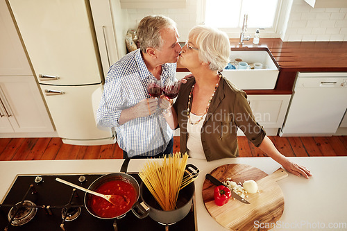 Image of Kiss, wine toast or old couple cooking food for a healthy vegan diet together with love in retirement at home. Top view of senior woman drinking or kissing in kitchen with mature husband at dinner