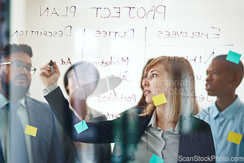 Image of Business people, glass wall and woman writing, planning and strategy in office. Sticky notes, brainstorming ideas and group of employees working on project, schedule and collaboration for teamwork.