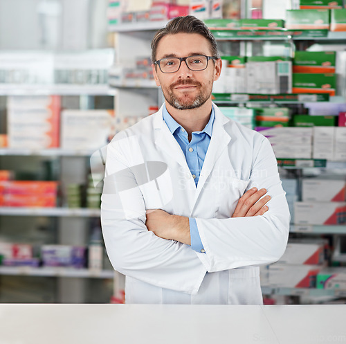 Image of Success, crossed arms and portrait of pharmacist in pharmacy clinic standing with confidence. Healthcare, medical and mature male chemist by the counter of pharmaceutical medication store dispensary.