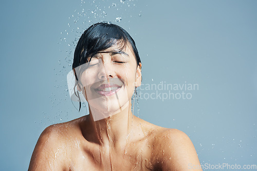 Image of Shower, washing and face of woman with water in studio on blue background for wellness, cleaning and grooming. Skincare, beauty mockup and happy female person for hygiene, hydration and self care