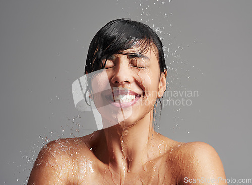 Image of Shower, water splash and face of woman in studio on gray background for wellness, cleaning and grooming. Skincare, beauty mockup and female person with smile for washing hair, body and cleansing