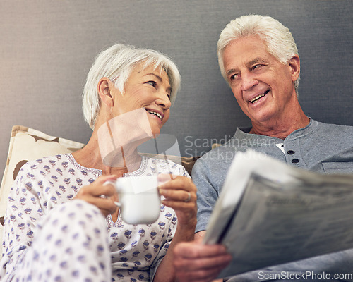 Image of Coffee, newspaper and a mature couple in bed, enjoying retirement in their home in the morning. Tea, reading or love with a happy senior man and woman in the bedroom together to relax while bonding
