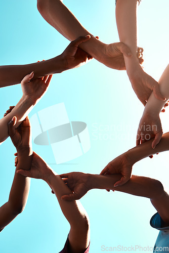 Image of Hands, link and circle with team and blue sky with low angle, solidarity and trust with arm chain and people together. Teamwork, motivation and connection with group collaboration and community