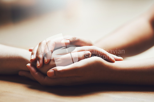 Image of Prayer, empathy and support with people holding hands in comfort, care or understanding on a wooden table of a home. Love, faith or depression with friends closeup for help, hope or peace for healing