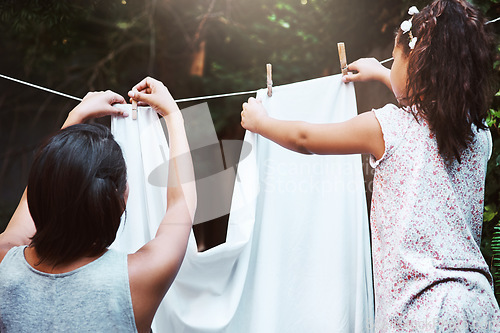 Image of Help, hanging laundry and a mother and child doing housework, chores and busy with clothes. Cleaning, family and back of a little girl helping mom with clothing on the line in the backyard together