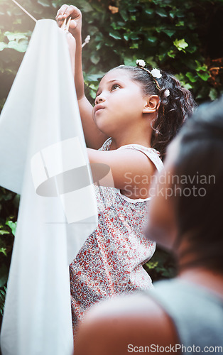 Image of Hanging clothes, help and a child with mother for laundry, housework and chores together. Teamwork, cleaning and a little girl helping mom at the clothing line for responsibility in the backyard