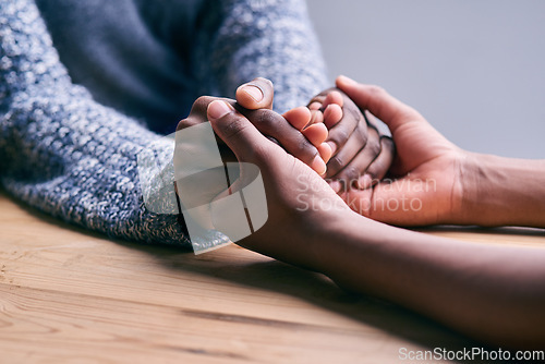 Image of Love, support and people holding hands for unity, compassion and sympathy by a wood table. Empathy, care and couple or friends with affection in an intimate bonding moment together for grief and loss