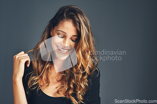 Image of Beauty, hair and happy with a woman in studio on a gray background for a natural or curly hairstyle. Salon, shampoo and smile with an attractive young female haircare model posing after treatment