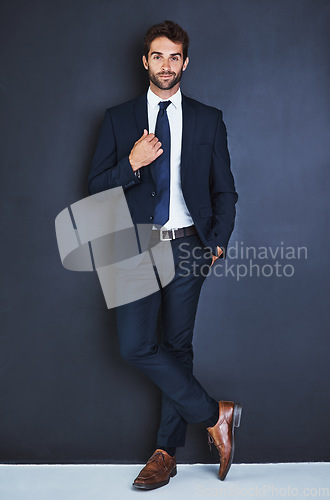 Image of Portrait, fashion and a formal business man in studio on a blue background for contemporary corporate style. Success, professional and a confident young male employee in a suit for executive power