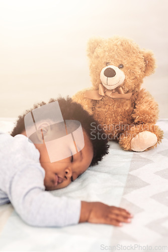 Image of Sleeping, teddy bear and tired with baby in bedroom for carefree, development and innocence. Dreaming, relax and comfortable with african infant and toy at home for morning, resting and bedtime