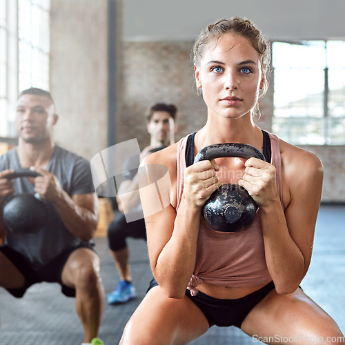 Image of Sports, kettlebell and woman doing a workout with a group for strength training in a gym. Fitness, energy and female athlete doing a exercise challenge with weights with people in a wellness center.