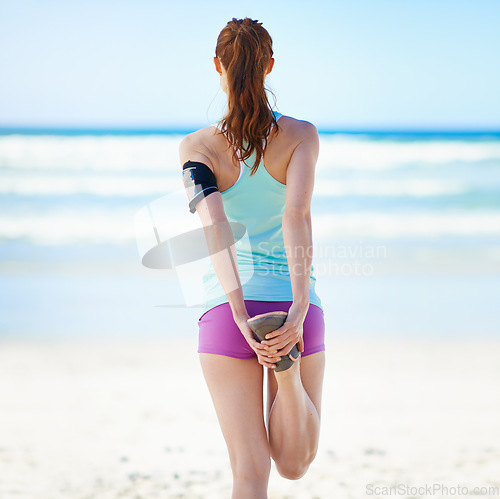 Image of Fitness, wellness or sports woman stretching leg for exercise warm up, cardio workout or training at beach sand. Back view, runner or athlete girl with health hamstring stretch at ocean with blue sky