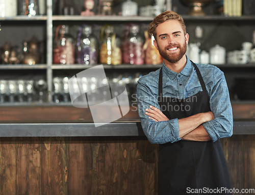 Image of Confidence, industry and portrait of male barista standing by the counter in his startup cafeteria. Smile, success and young man with crossed arms with a small business coffee shop or restaurant.