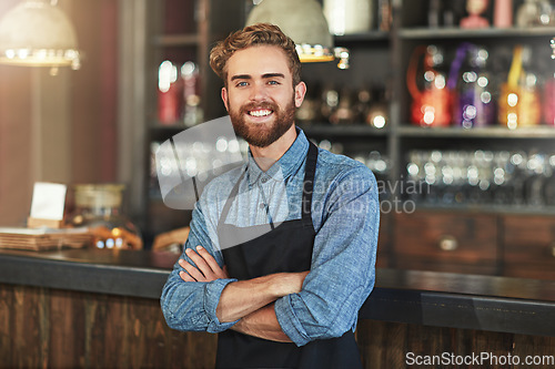 Image of Happy, smile and portrait of coffee shop owner standing by the counter in his startup cafeteria. Happiness, success and male barista with small business with crossed arms for confidence in restaurant