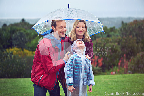 Image of Family, happy and outdoor in rain with umbrella in nature for fun, happiness or quality time. Man, woman and excited child with cover for water drops with freedom, love and care while playing at park