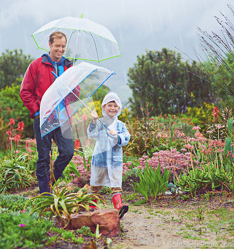 Image of Rain, umbrella and nature with a father and child outdoor for family fun, happiness and quality time. Happy man and kid walking on adventure with water drops, freedom and play for learning in garden