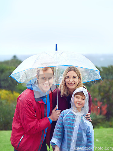 Image of Rain, outdoor and a happy family with umbrella for a portrait in nature for fun, happiness and quality time. Man, woman and boy child together for water drops and freedom while playing at a park