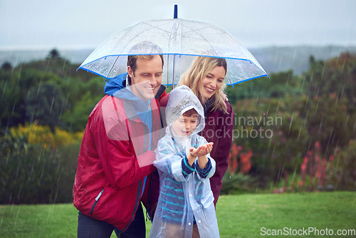Image of Rain, umbrella and a happy family outdoor in nature for fun, happiness and quality time. Man, woman and excited child together with hands to catch water drops while learning, playing or development