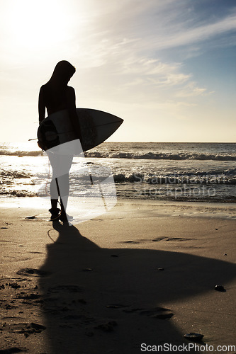 Image of Silhouette, woman surfer on beach sand and ocean, exercise outdoor and healthy with surfboard and scenic sea view. Sports, shadow and sun with female person in nature and ready to surf for fitness