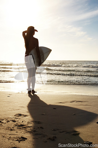 Image of Silhouette, woman surfer on beach sand and sea, exercise outdoor and healthy with surfboard and scenic ocean view Sports, shadow and sun with female person in nature and ready to surf for fitness