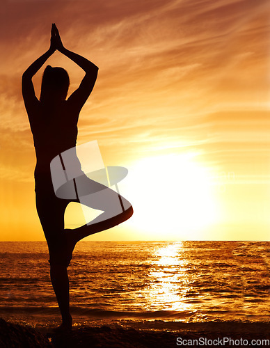 Image of Silhouette, sunset and woman in tree pose with yoga on the beach, orange sky and fitness outdoor. Meditation, wellness and peace in nature with shadow, female yogi person and pilates by the ocean