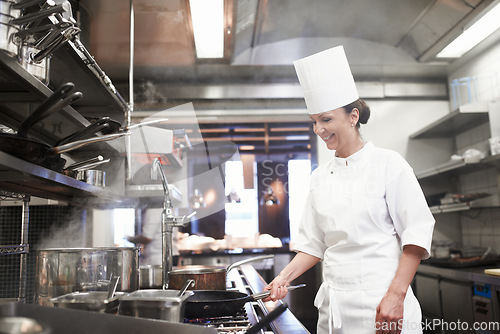 Image of Restaurant, cooking and a woman chef in the kitchen for luxury hospitality or preparation of a gourmet meal. Food, catering and a professional female cook working in the commercial service industry
