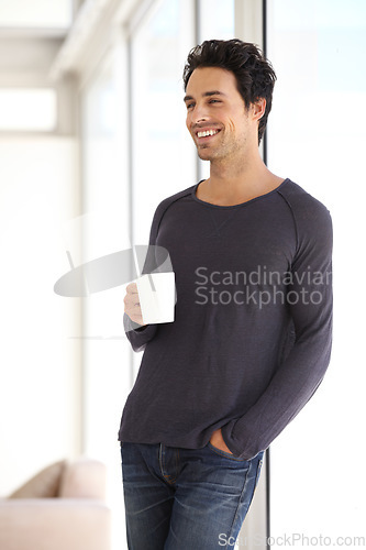 Image of Happy, smile and man with a cup of coffee standing by the window in a vacation house. Calm, relax and attractive male person drinking a latte in a mug in the living room while thinking or in a dream.