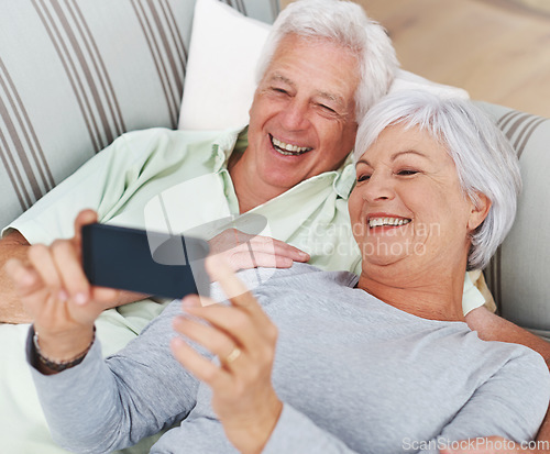 Image of Senior, happy couple and relax for selfie on sofa in living room with smile for photo, memory or profile picture at home. Elderly man and woman smiling for photograph, vlog or social media on couch