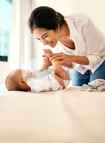 Image of Smile, love and a mother with her baby in the bedroom of their home together for playful bonding. Family, kids and a happy young mama spending time with her newborn infant on the bed for fun or joy