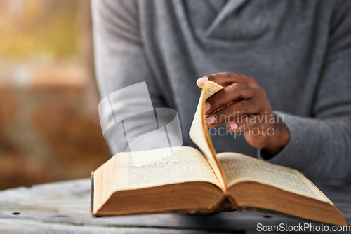 Image of Hands, spiritual and a man reading the bible at a table outdoor in the park for faith or belief in god. Book, story and religion with a male christian sitting in the garden for learning or worship