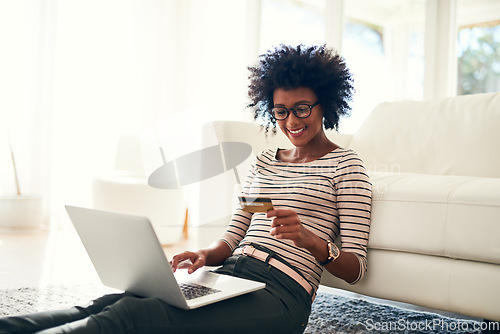 Image of Young woman, laptop and credit card on living room rug doing online shopping sitting on ground. Home, happiness and computer with African female person on a ecommerce app reading information to buy