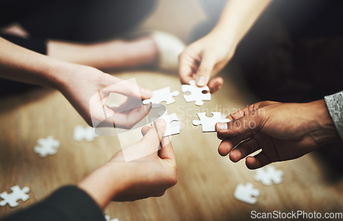 Image of Hands, business people and puzzle in circle, closeup and teamwork for problem solving, solution and game. Group, together and helping hand for jigsaw, solidarity and team building on office floor