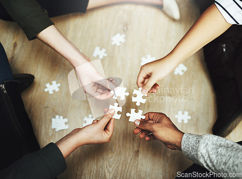 Image of Hands, business people and puzzle in circle, huddle or teamwork for problem solving, solution or game in top view. Group, together and helping with support, synergy and team building on office floor