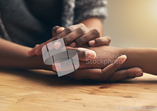 Image of Comfort, sympathy and people holding hands for unity, compassion and cancer support at wood table. Empathy, care and couple or friends with affection in bonding moment together for grief and loss.