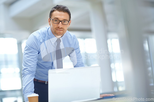 Image of Portrait, laptop and mission with a businessman working on research in his office for a report. Computer, mindset and vision with a male employee working on innovation or planning for success