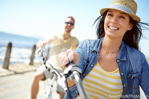 Image of Bike, cycling and couple with a travel woman on summer vacation or holiday riding on the promenade by the beach. Freedom, date and romance with a girlfriend outdoor for a ride on the coast