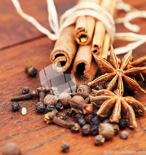 Image of Indian spices, cooking ingredient and table with kitchen herbs for curry and biryani. Wood tabletop, healthy diet and closeup with cinnamon, pepper and cloves for Mediterranean cuisine with cumin