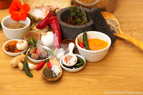 Image of Mortar, food and spices on table for cooking gourmet meal, chili seasoning or flavor pestle. Pepper vegetables, kitchen condiments and variety of plant herbs for brunch, healthy diet or vitamins.